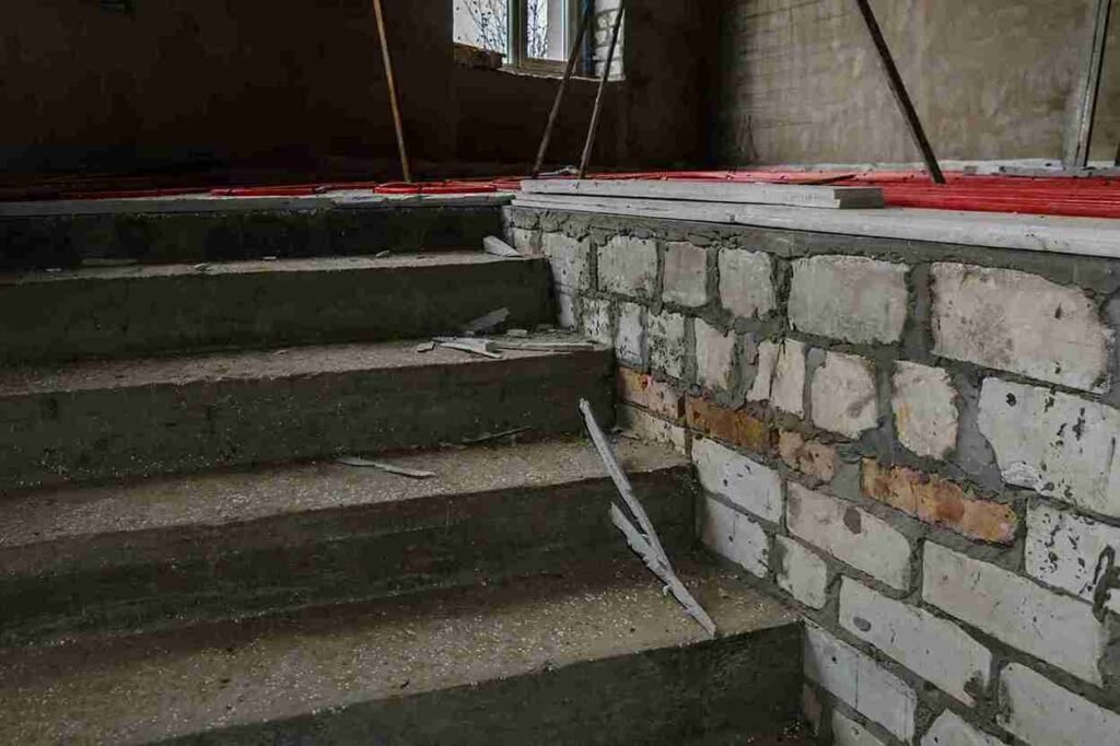 Concrete stairs under renovation with exposed stone wall in a North Royalton OH property.