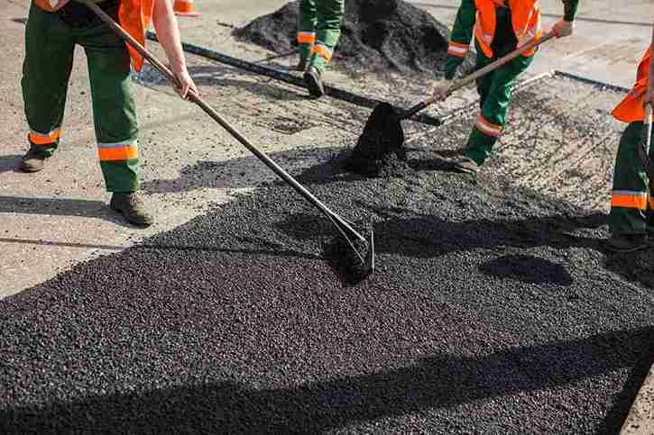 Workers spreading and leveling asphalt during driveway installation in North Royalton OH.